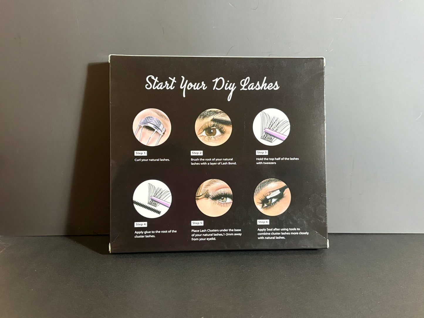 Instructions for DIY eyelash application on a black box against a gray background